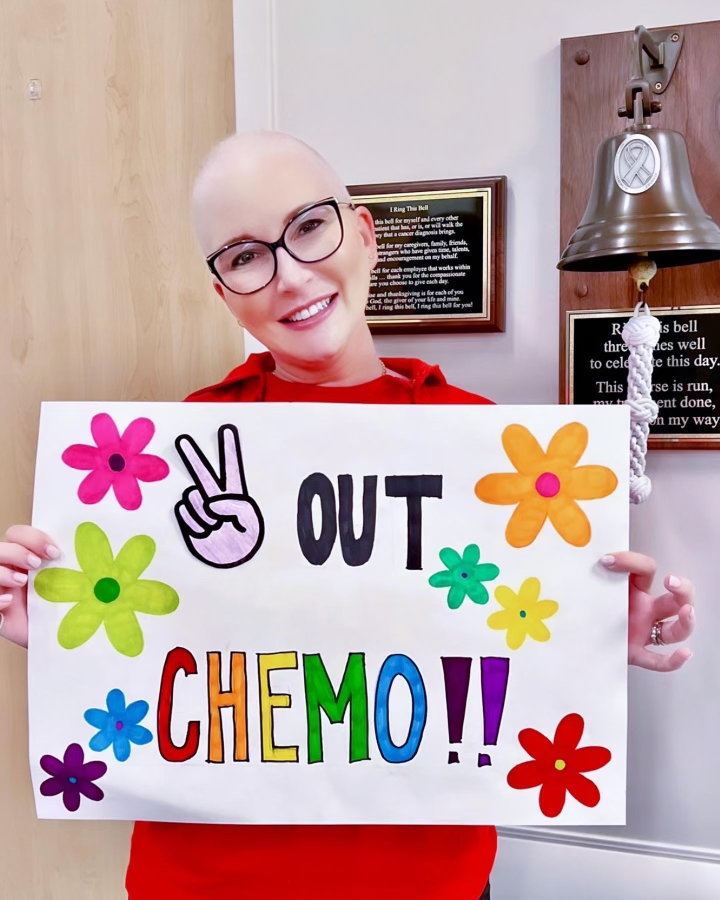 Clea with a sign that reads 'peace out chemo'